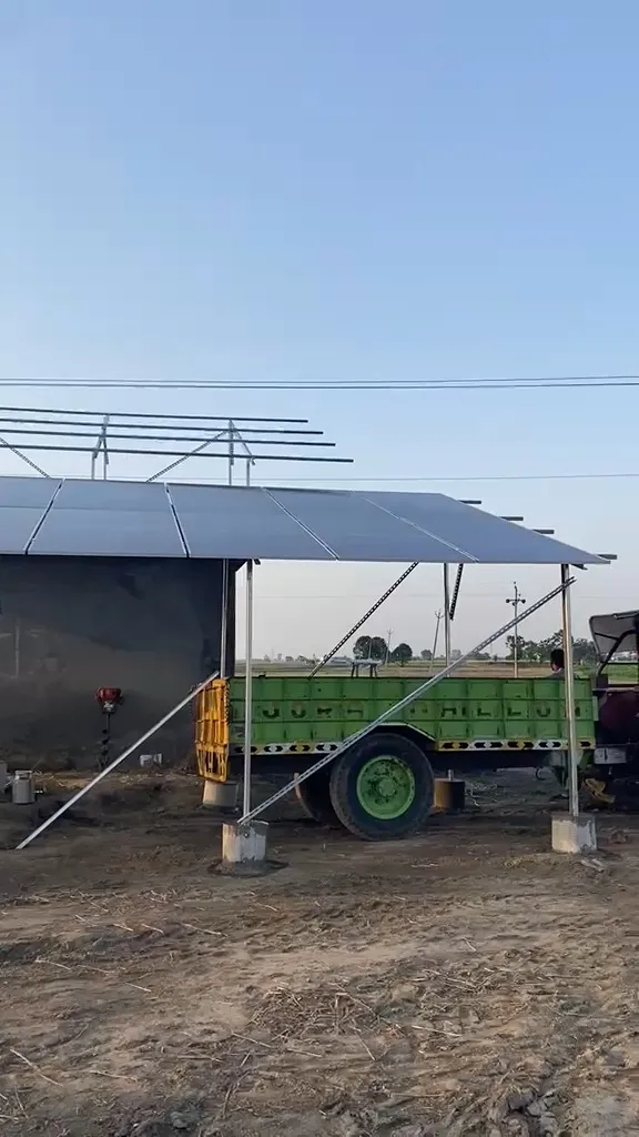 Solar panels mounted over a farm shed in Punjab with a tractor trailer parked underneath