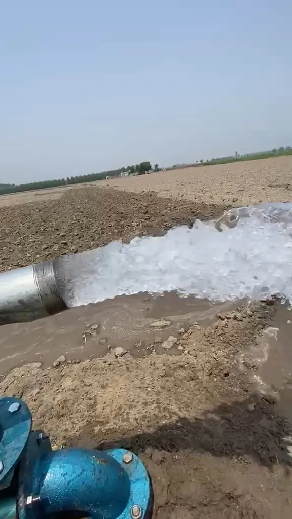 Water discharging from a solar tubewell pump onto a ploughed field in Punjab