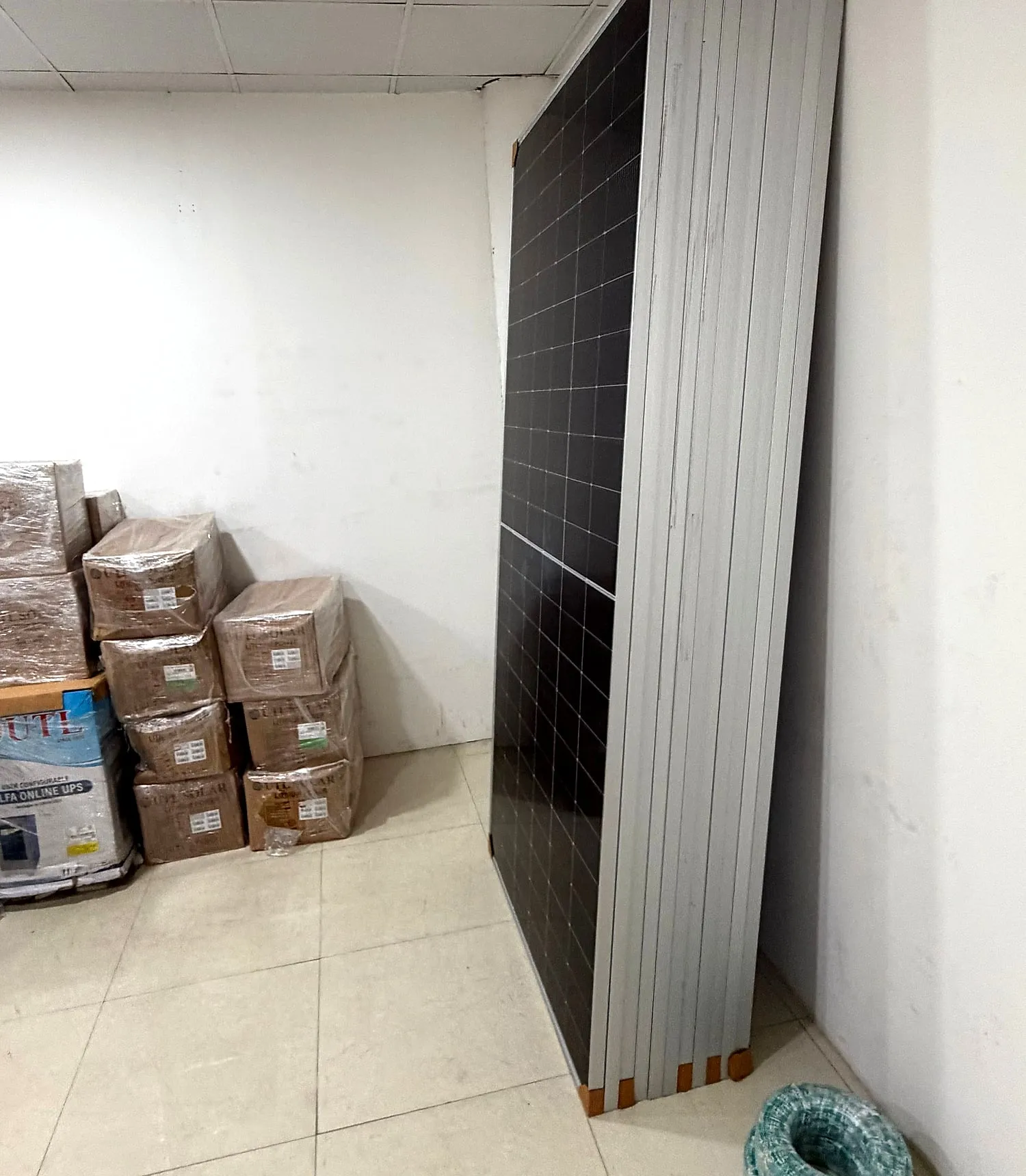 A stack of solar panels leaning against the wall in the RSK Solar Energy store room